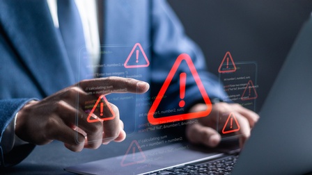 Fokus auf Hand einer Person, die über Tastatur zeigefinger streckt, über das gesamte Bild Overlay mit roten Rufzeichen in Dreiecken