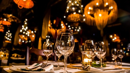 Gedeckter eleganter Tisch bei gedämpften Licht in einem luxuriösen Restaurant