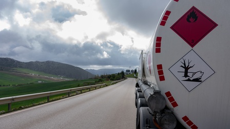 Tanker transportiert Gefahrengut auf Bundesstraße, auf weißem Tank sind Gefahren-Plaketten montiert