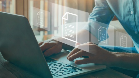 Eine Person sitzt an einem Tisch an einem aufgeklappten Laptop. Über dem Laptop sind als Grafik vier weiße Zettel nebeneinander. Auf jedem Zettel sind Linien und Häkchen. Die Person tippt auf dem Laptop