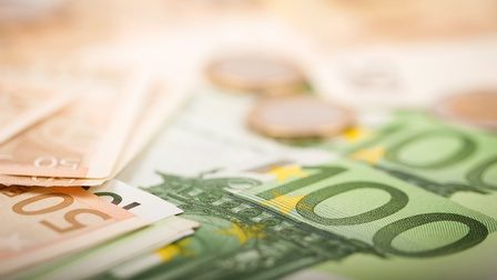 Detailansicht von 100- und 50-Euro-Gelscheinen, zwei Euromünzen verschwommen