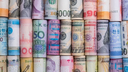 Detailaufnahme von zusammengerollten Geldscheinen aus unterschiedlichen Währungen von verschiedenen Ländern der Welt