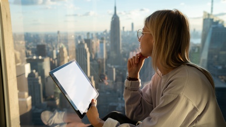Junge Unternehmerin blickt mit Tablet in der Hand auf New York