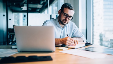 Person sitzt vor Laptop und arbeitet