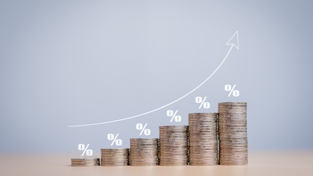 Mehrere unterschiedlich hohe Münzstapel der Größe nach aufsteigend nebeneinander positioniert, darüber jeweils weiße Prozentzeichen, schräger Strich mit links und rechts versetzter 0, sowie Pfeil der über den Stapeln nach oben deutet