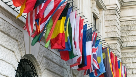 Verschiedene Länderflaggen nebeneinander an Hausfassade befestigt