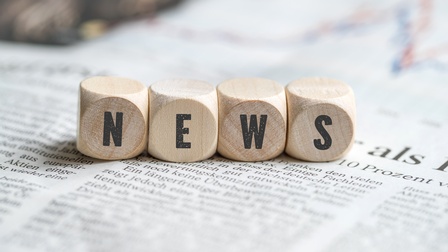 Holzwürfel nebeneinanderliegend auf Zeitung, die Schriftzug News ergeben