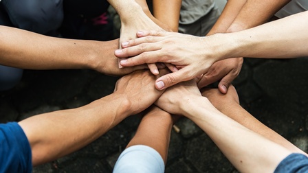 Nahaufnahmen von mehreren Händen von Personen in einem Kreis übereinander gestapelt