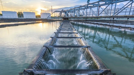 Wasseraufbereitungsanlage an einem Fluss mit Sonnenuntergang im Hintergrund