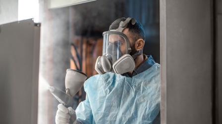 Porträt einer Person mit Vollgesichtsmaske in Overall besprüht mit Farbsprühsystem Oberfläche