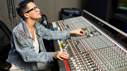 Person mit Brille bedient Mischpult