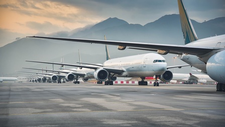 Auf einer sehr großen, asphaltierten Fläche stehen sehr viele Flugzeuge hinter- und nebeneinander. Im Hintergrund sind Berge