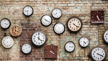 Viele verschiedene große und kleine Vintage Uhren hängen auf einer Ziegelwand