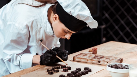 Chocolatière bei der Herstellung von Schokoladenpralinen