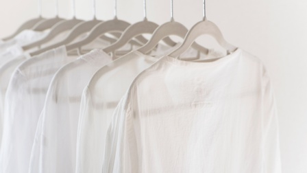 Mehrere Leinenhemden hängen geordnet auf weißen Kleiderbügeln