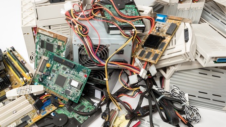 Detailansicht Elektroschrott: Haufen mit Computertastaturen, Festplatten, Kabeln und Drucker
