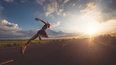 Sprinter auf Straße der Sonne entgegen laufend