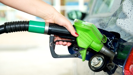 Hand hält Tankstutzen in die Öffnung eines Autotanks