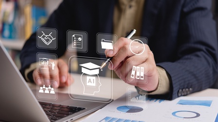 Eine Person sitzt an einem Schreibtisch vor einem Laptop und hält einen Stift in der Hand. Über dem Bild sind transparente Symbole eingeblendet, darunter KI, Ordner, Uhr, Diagramme, Team oder Dokumente