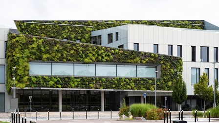Modernes Gebäude mit großen Glasfronten und üppiger Fassadenbegrünung