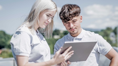 Zwei Personen lesen auf einem Tablet