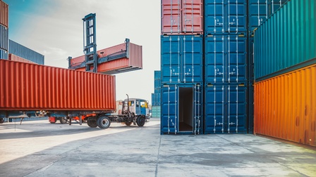 Gestapelte Container bereit für die Verschiffung, ein LKW wird mit Container beladen