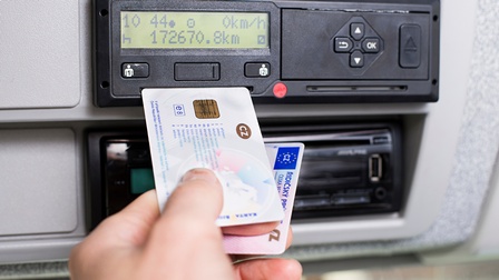 Fahrtenschreiber und Hand, die eine Fahrerkarte und einen Führerschein gemeinsam hält