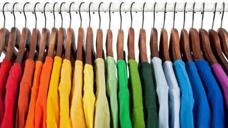 Detailansicht bunter T-Shirts an einer Wäschestange hängend
