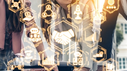 Im Ausschnitt mehrere Personen an Tisch versammelt, sich darauf abstützend, leuchtendes Overlay mit verschiedenen Symbolen wie zum Beispiel Handschlag