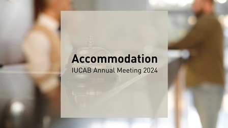 Analoge Rezeptionsklingel auf Tresen, im Hintergrund verschwommen Personen