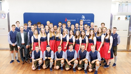 Porträt von vielen Jugendlichen, die entweder eine Lederhose oder ein Dirndl tragen. Hinter ihnen ist ein dunkelblaues Plakat, auf dem Skills Austria steht