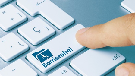 Finger drückt auf deine Taste einer Tastatur mit Aufschrift barrierefrei und Icon einer Person im Rollstuhl mit einem Ordner
