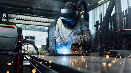 Eine Person in Schutzausrüstung schweißt Platten in einer Werkstatt