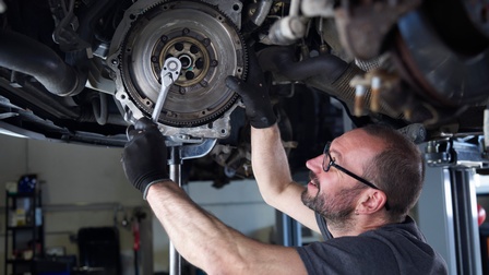 Ein Mann steht unter einem Auto und schraubt an einem Radflansch