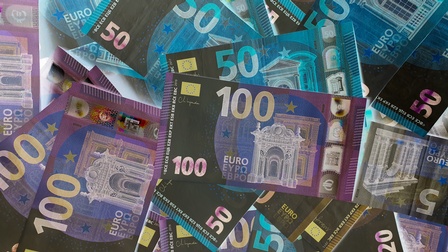 Detailansicht mehrerer Euro-Banknoten auf einem Haufen, farblich ins Negativ invertiert