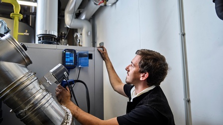 Ein Rauchfangkehrer kontrolliert mit dem Messgerät Wert im Heizungskeller an einem Rohr