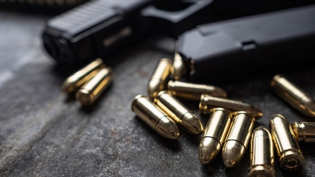 Nahaufnahme einer Waffe und loser Munition daneben