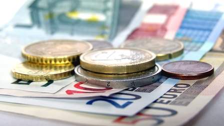 Detailansicht von 10-, 20- und 50-Euro-Geldscheinen auf denen verschiedene Euromünzen liegen.