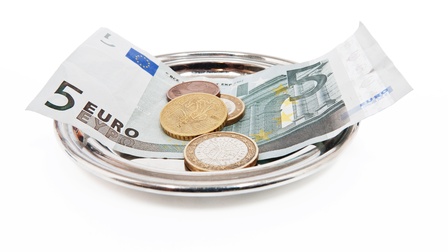 Nahaufnahme eines runden, kleinen Metalltellers, auf dem eine Rechnung ein Fünf-Euroschein und ein paar Münzen sind