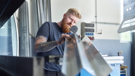 Ein Mann kontrolliert den Winkel eines gefalteten Stahlteiles 