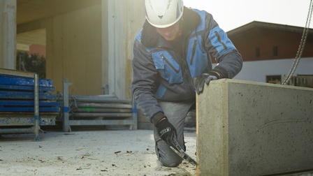 Ein Mann hämmert auf einer Baustelle die Verschalung von einem Betonteil