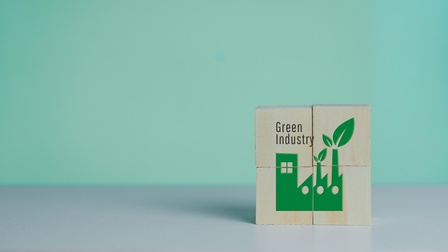 Auf Holzwürfeln ist eine grüne Fabrik aufgezeichnet. Daneben steht Green Industry
