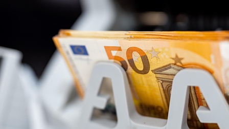 Mehrere 50 Euro Geldscheine liegen in einer Geldzählmaschine