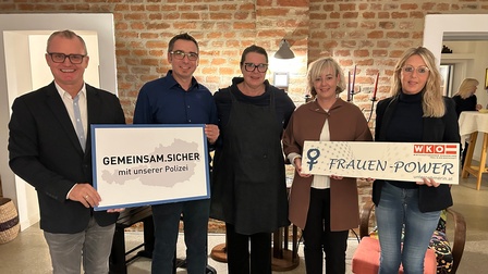 Fünf Personen halten grinsend ein Schild mit dem Titel 