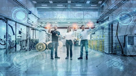 zwei Männer und eine Frau vor einer virtuellen Wand in einem Industriebetrieb