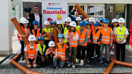 WK-Bezirksobmann Michael Gitterle (l.) und WK-Bezirksstellenleiter Otmar Ladner (r.) mit Schüler:innen aus dem Bezirk Landeck beim Lokalaugenschein der Erlebniswelt Baustelle.