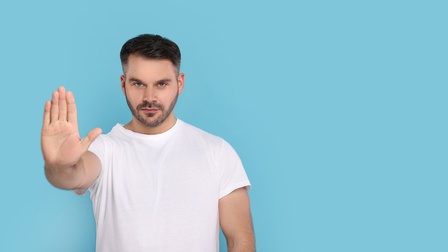 Ein Mann macht eine abwehrende Geste mit seiner Hand