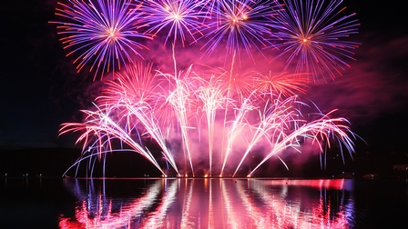 Violettpinkes Feuerwerk spiegelt sich auf Wasseroberfläche