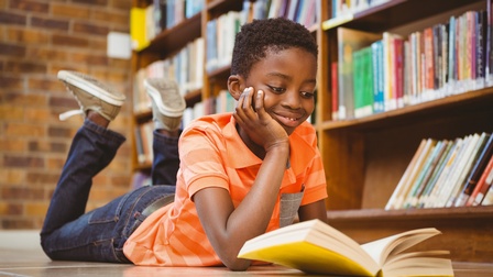 Junge liegt auf dem Boden und liest ein Buch