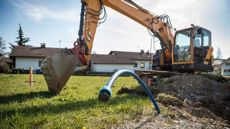 Bagger gräbt Schacht für Leitung